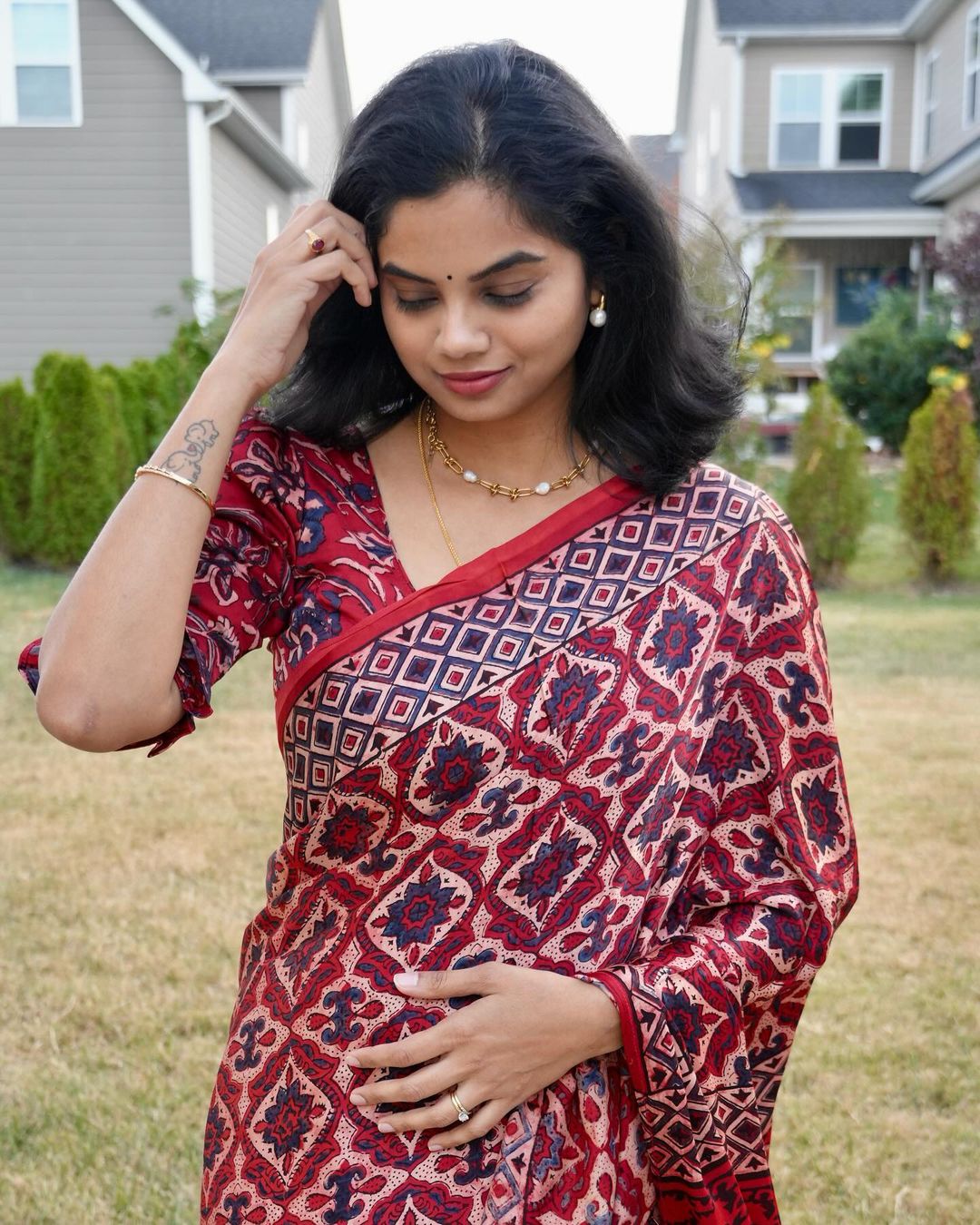 Kawaii ajrakh saree in red and blue geometric patterns worn by a woman with jewelry outdoors